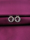 Silver round bow earrings with clear stones on a purple fabric background