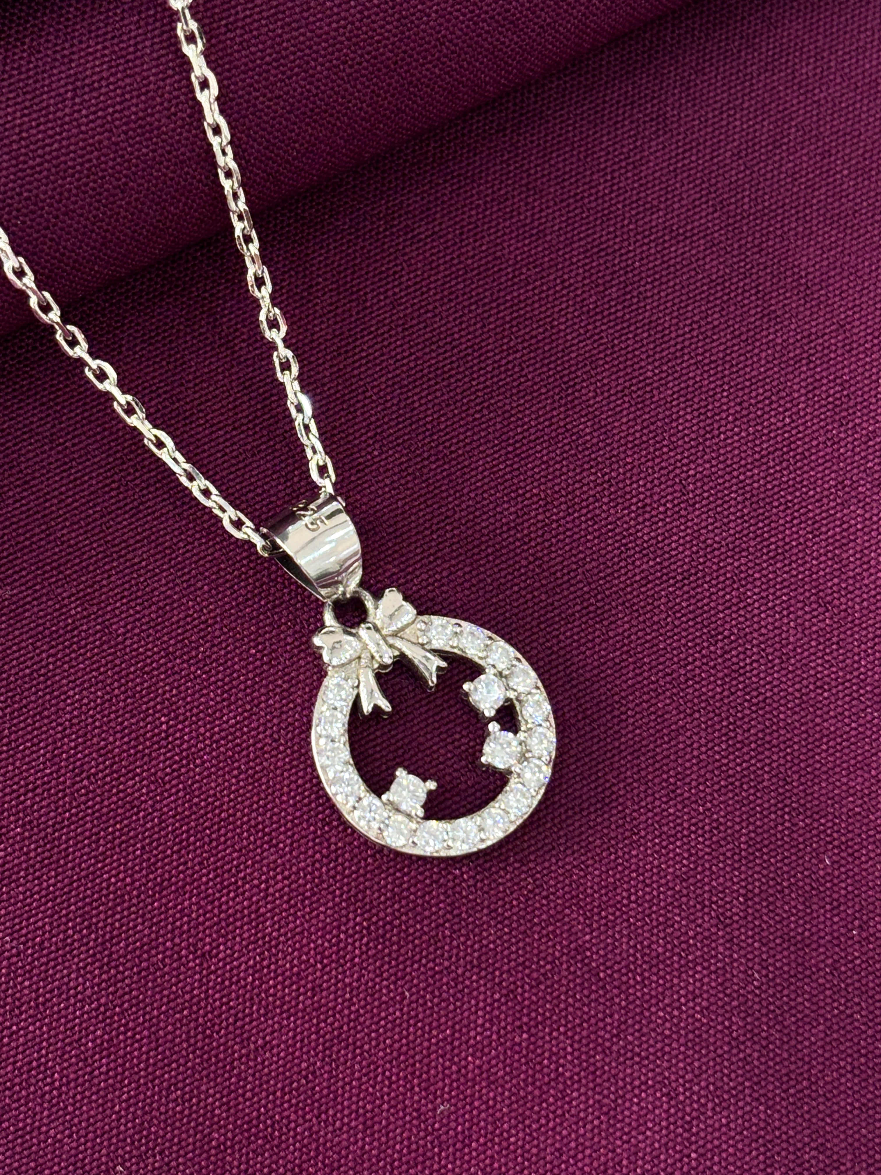 Silver necklace with a circular pendant on a purple fabric background