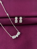 Silver jewelry set with necklace and earrings on a purple fabric background