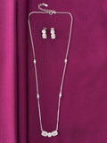 Silver necklace and earrings on a purple fabric background