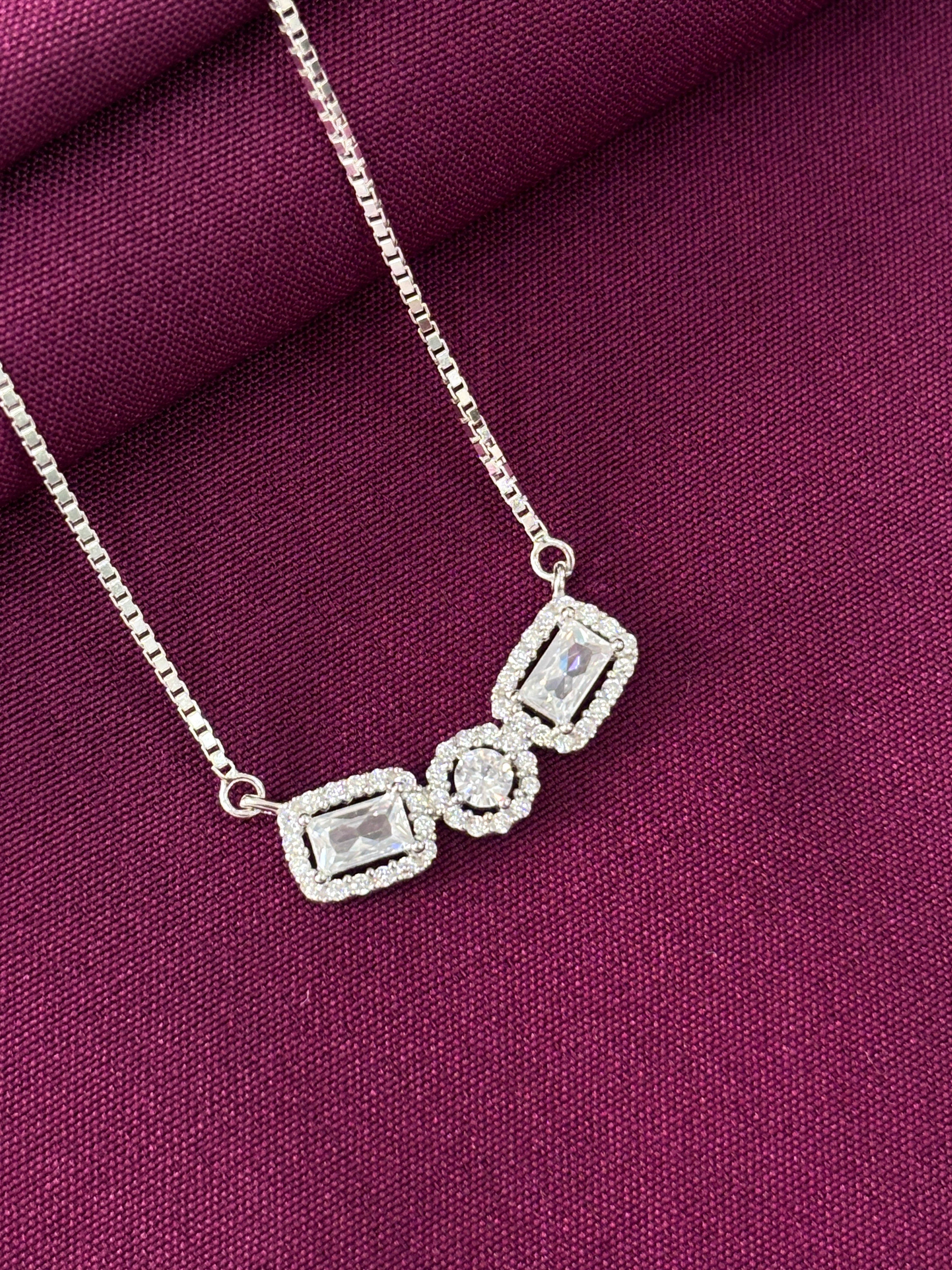 Silver necklace with diamond-like stones on a purple fabric background