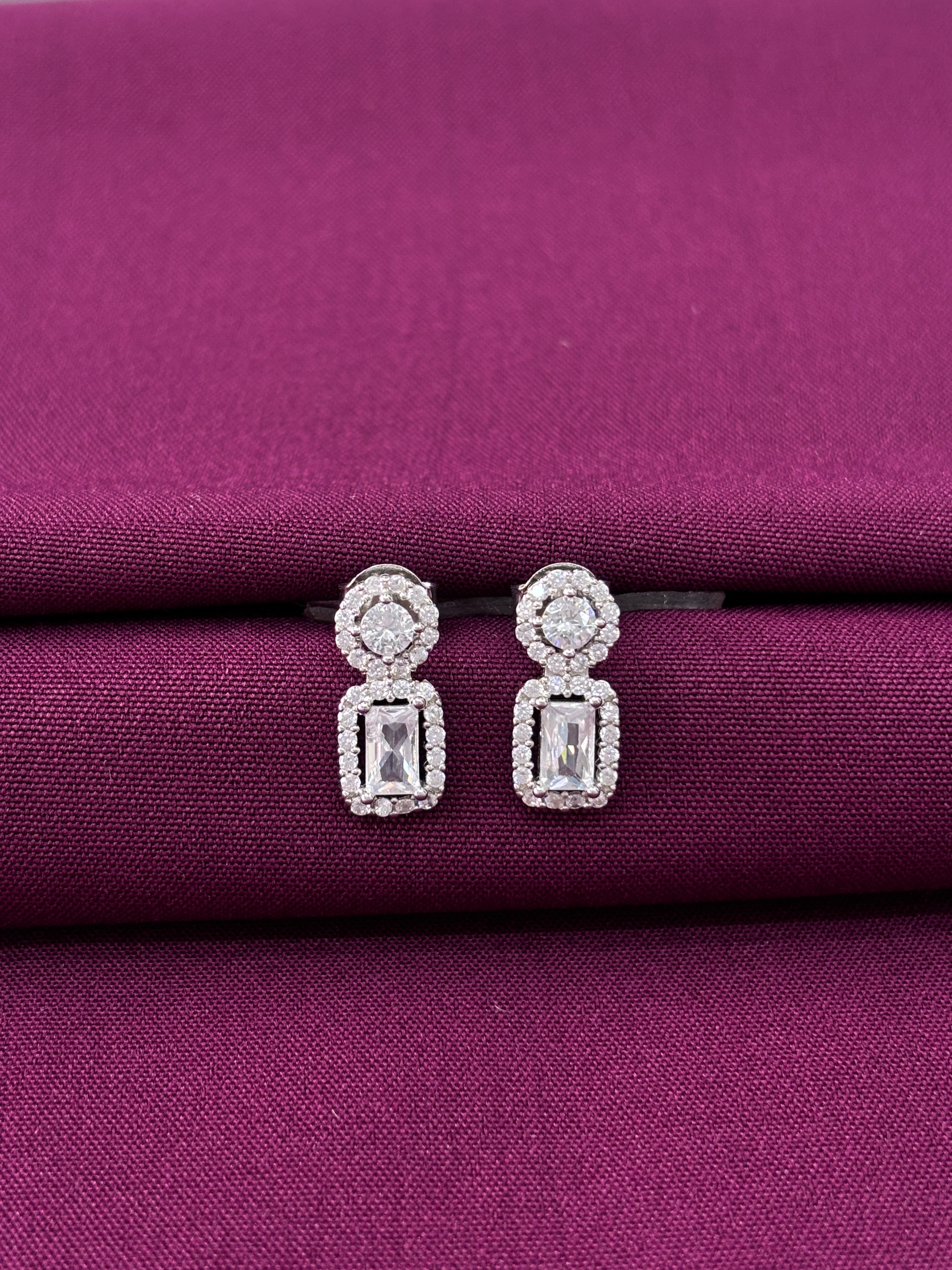 Pair of diamond earrings on a purple fabric background