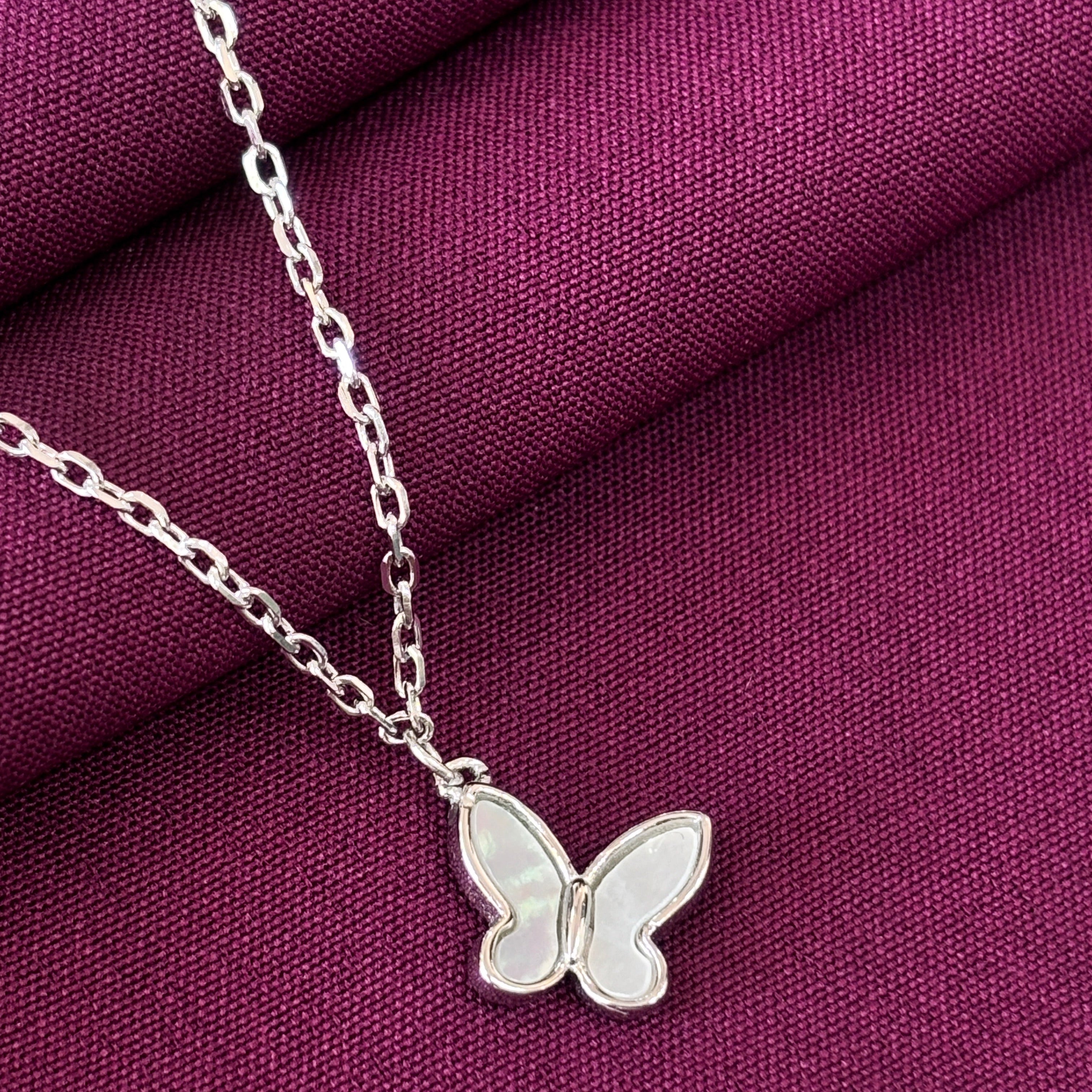 Silver necklace with a butterfly pendant on a purple fabric background