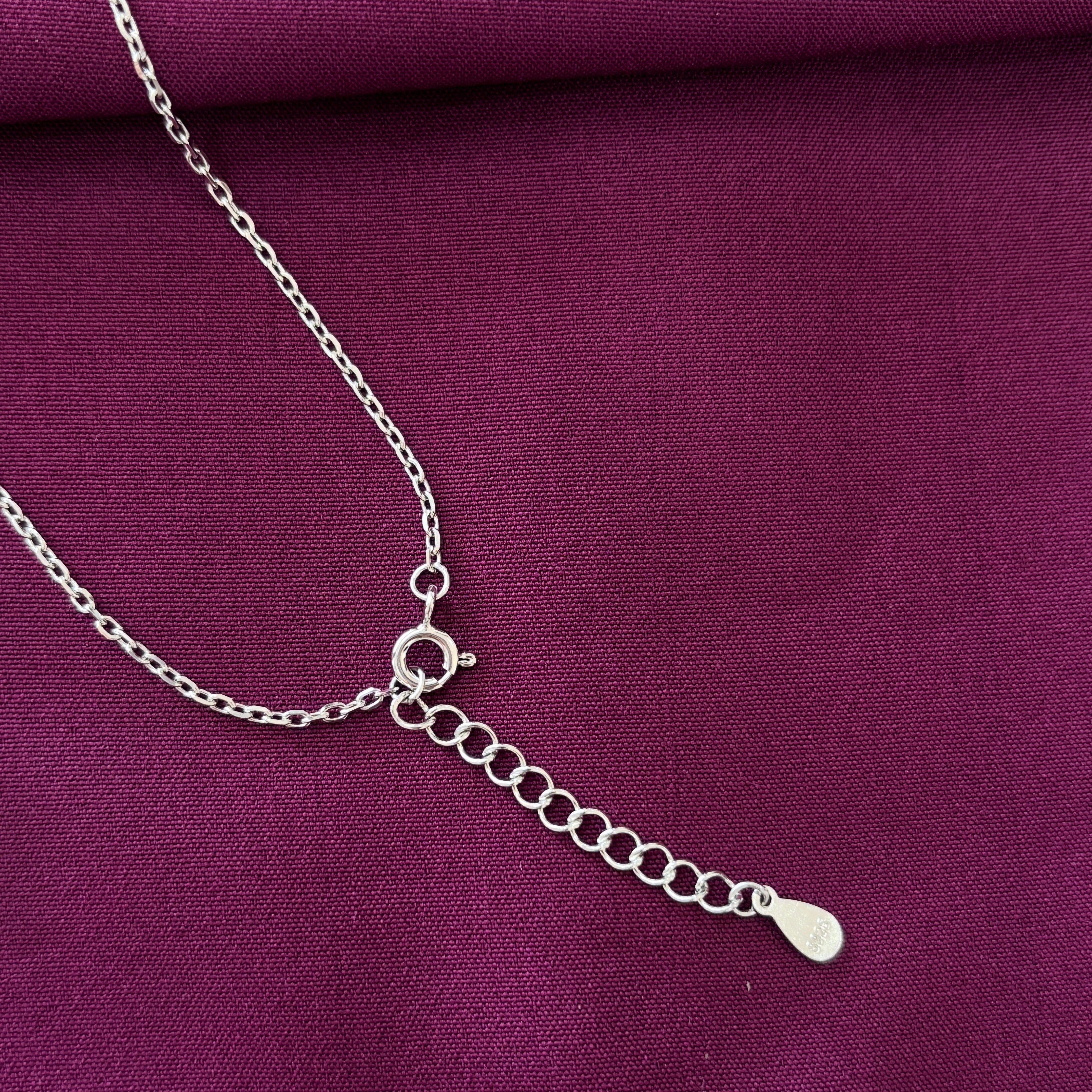 Silver chain necklace on a purple fabric background