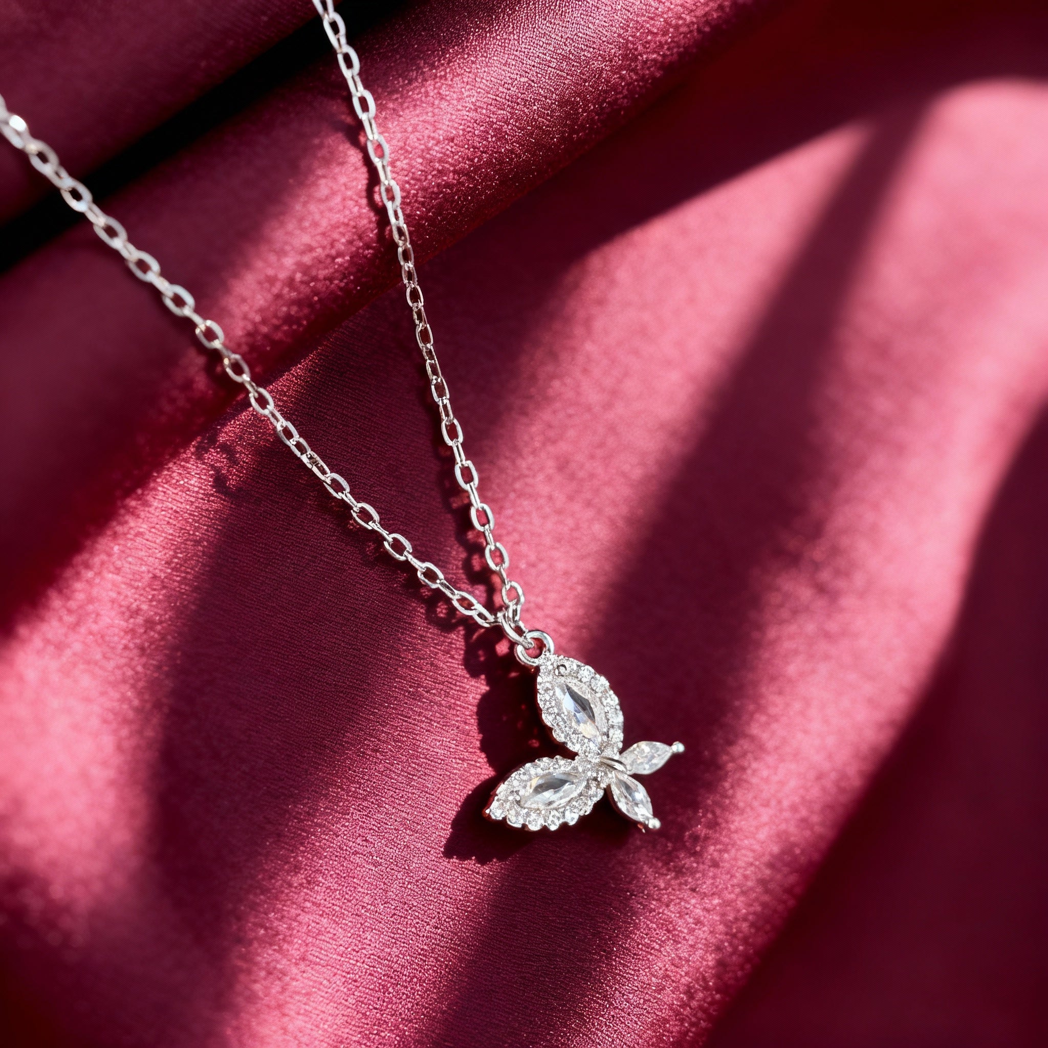 Silver necklace with leaf design on a red fabric background