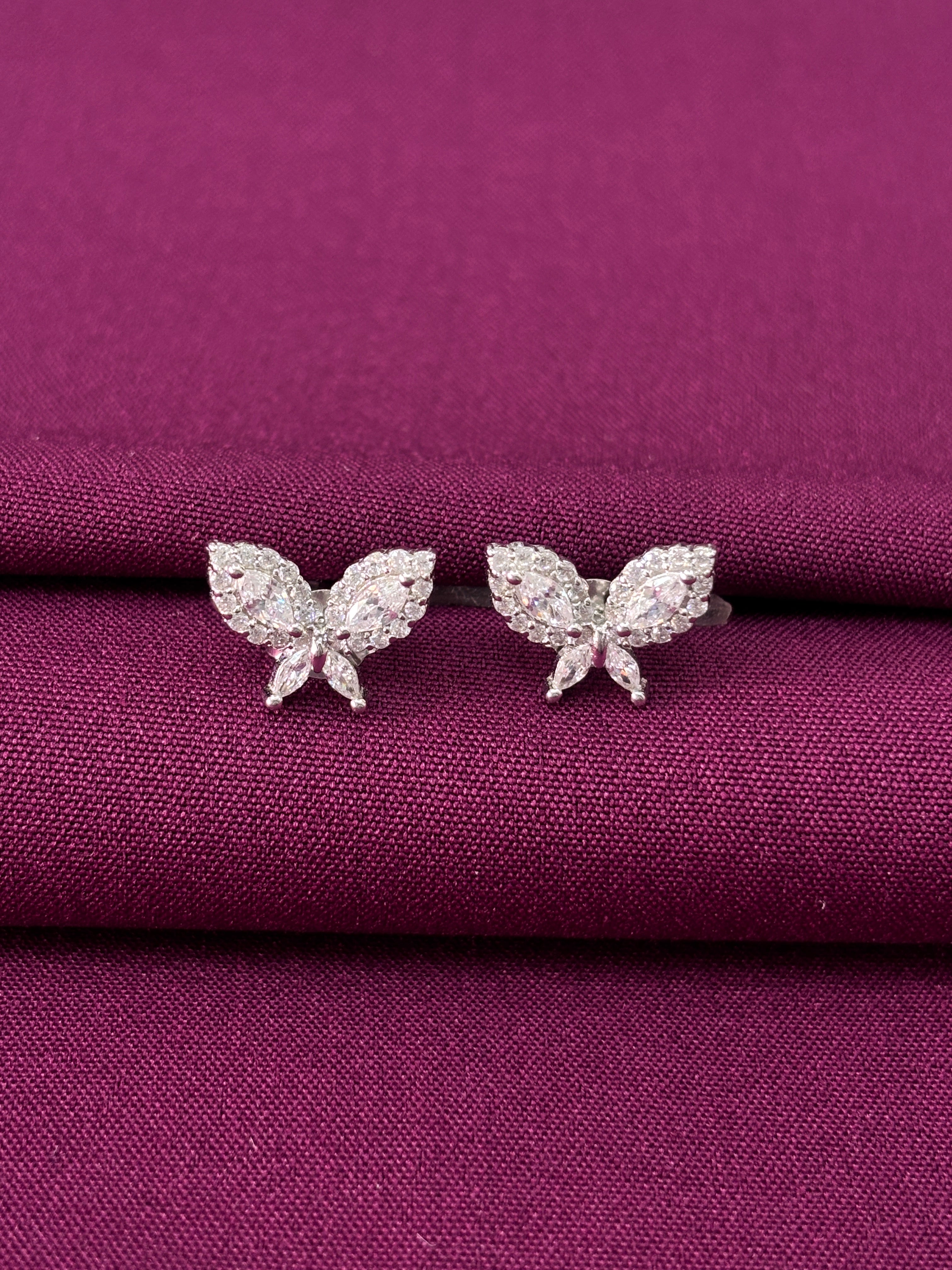 Butterfly-shaped earrings on a purple fabric background