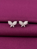 Butterfly-shaped earrings on a purple fabric background