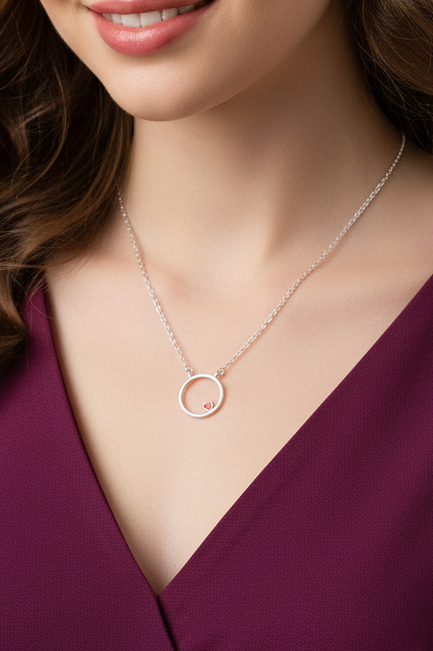 Necklace with a circular pendant worn by a person in a purple top