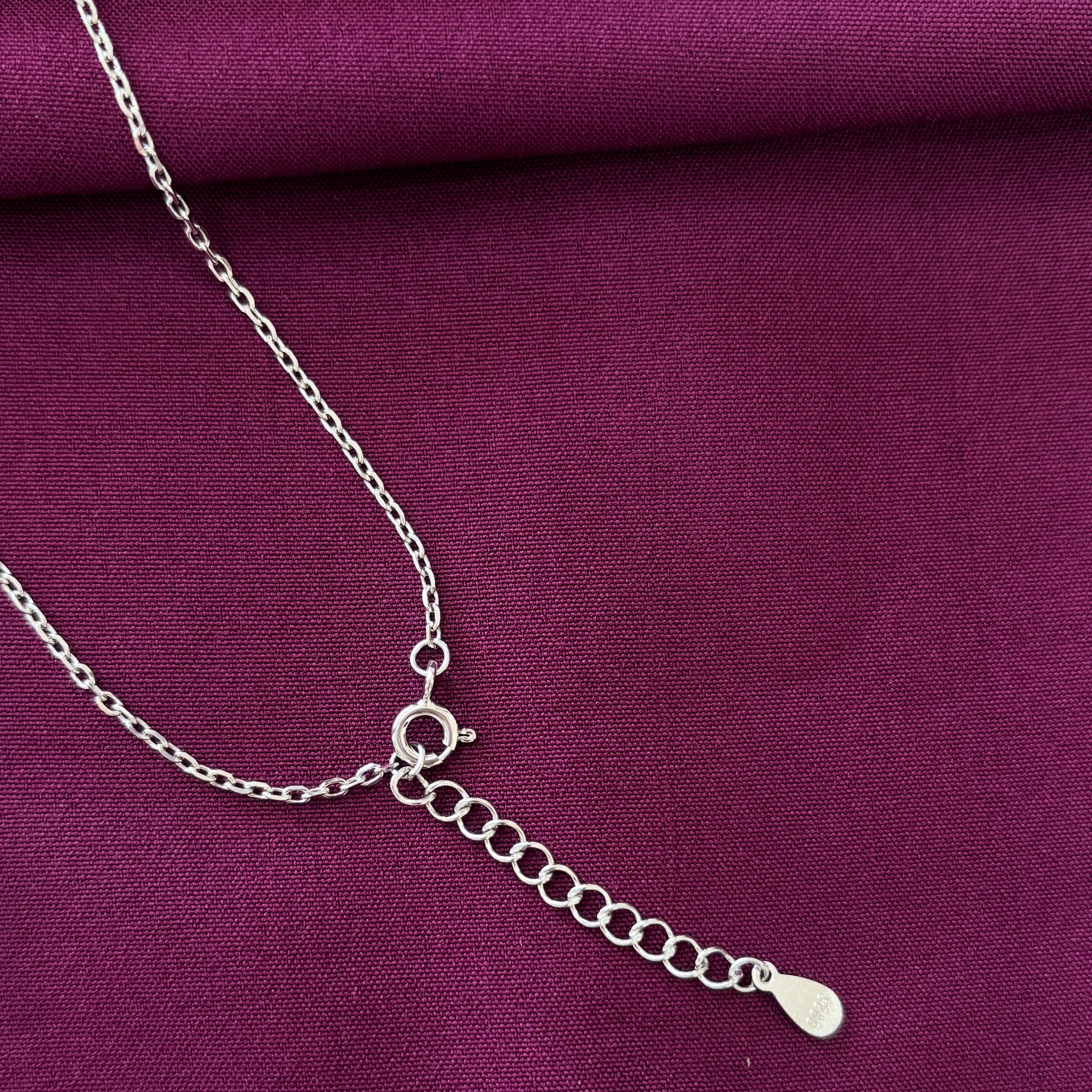 Silver chain necklace on a purple fabric background