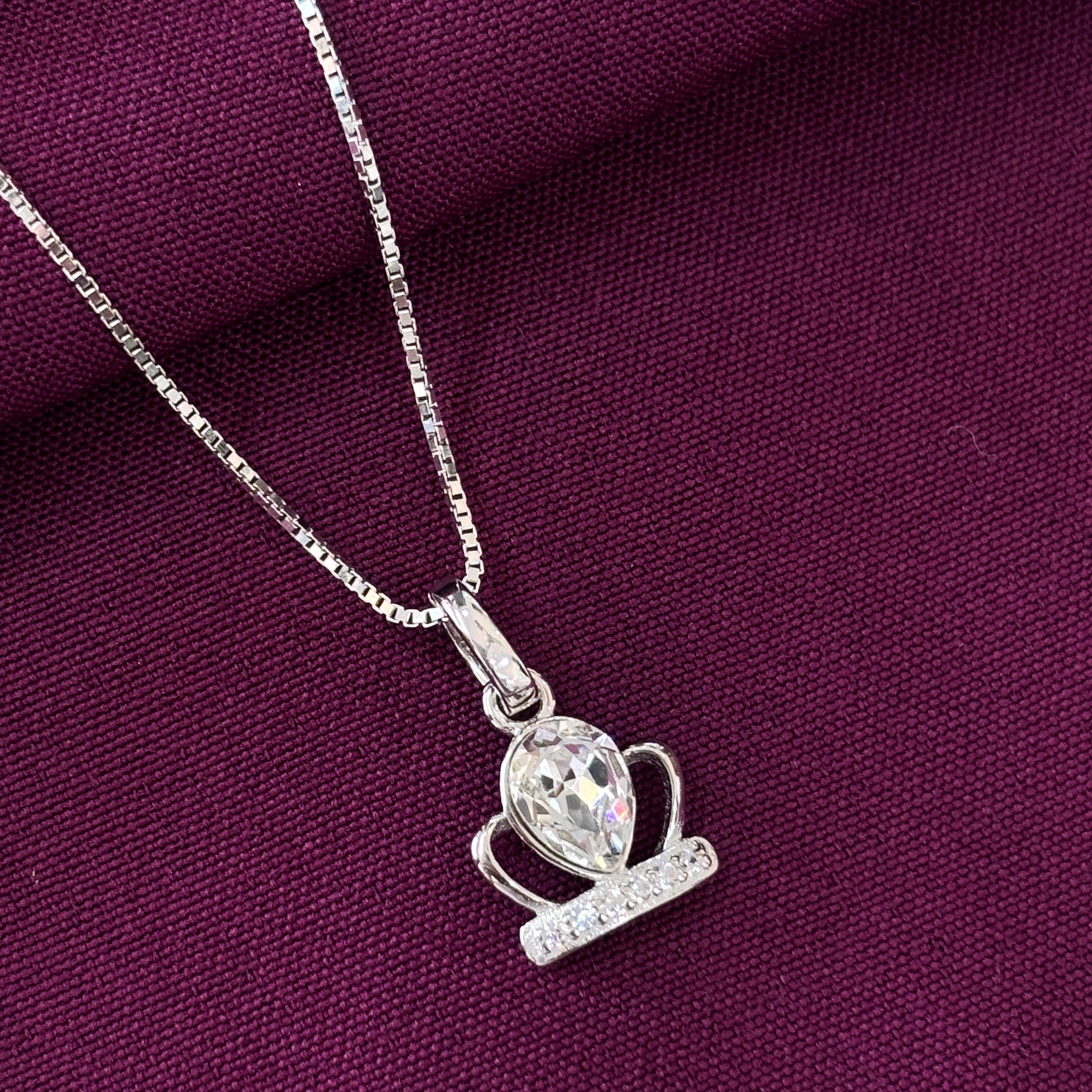 Silver necklace with a pendant on a purple fabric background