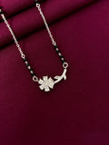 mangalsutra with a floral pendant on a maroon fabric background