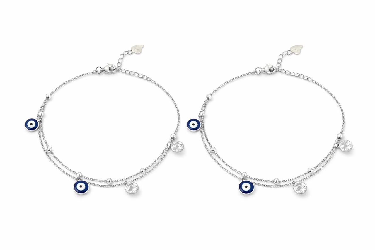 Two silver payal with blue evil eye charms on a white background