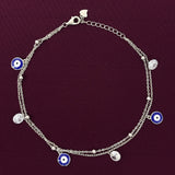 Silver payal with blue evil eye charms on a dark purple background