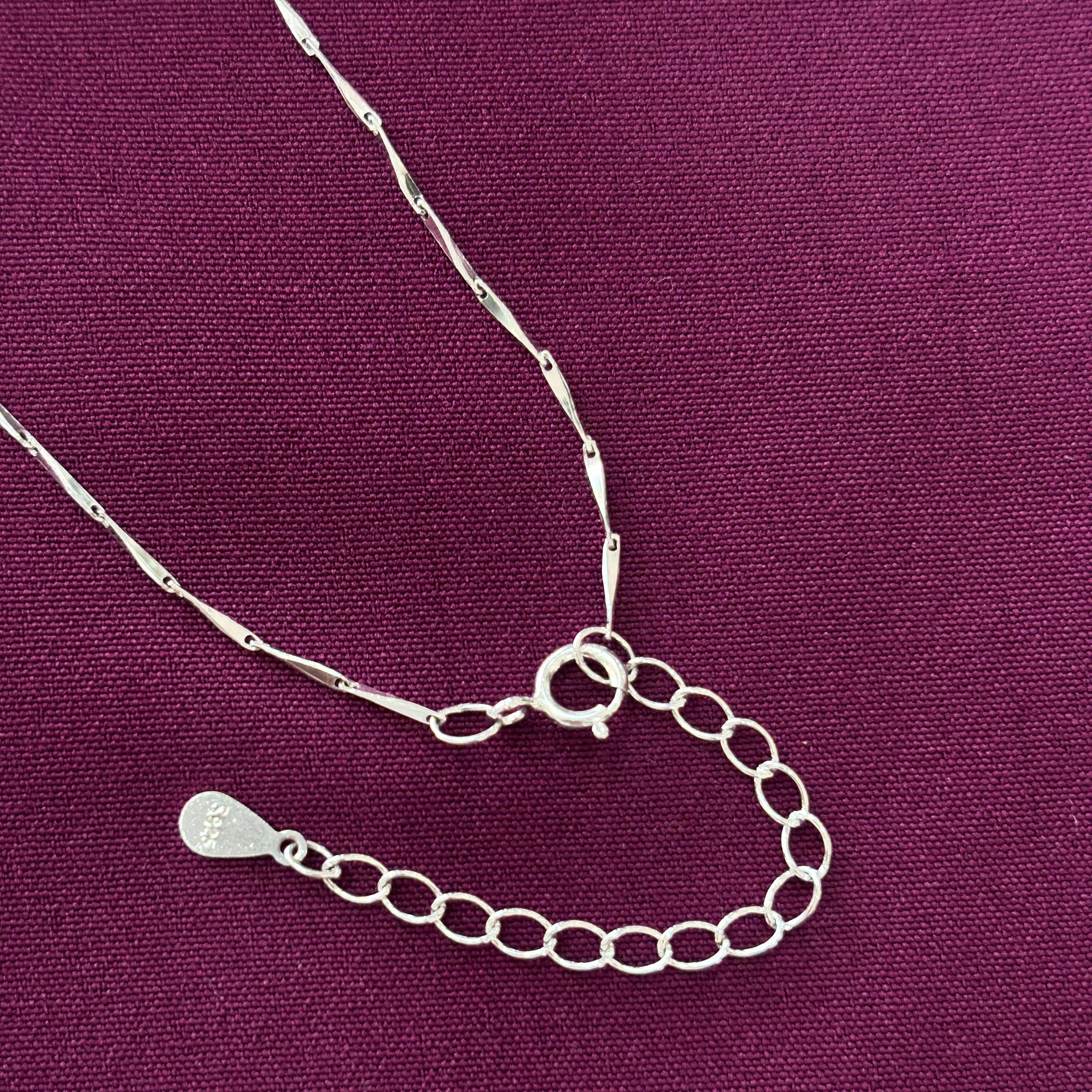 Silver necklace with a clasp on a purple fabric background
