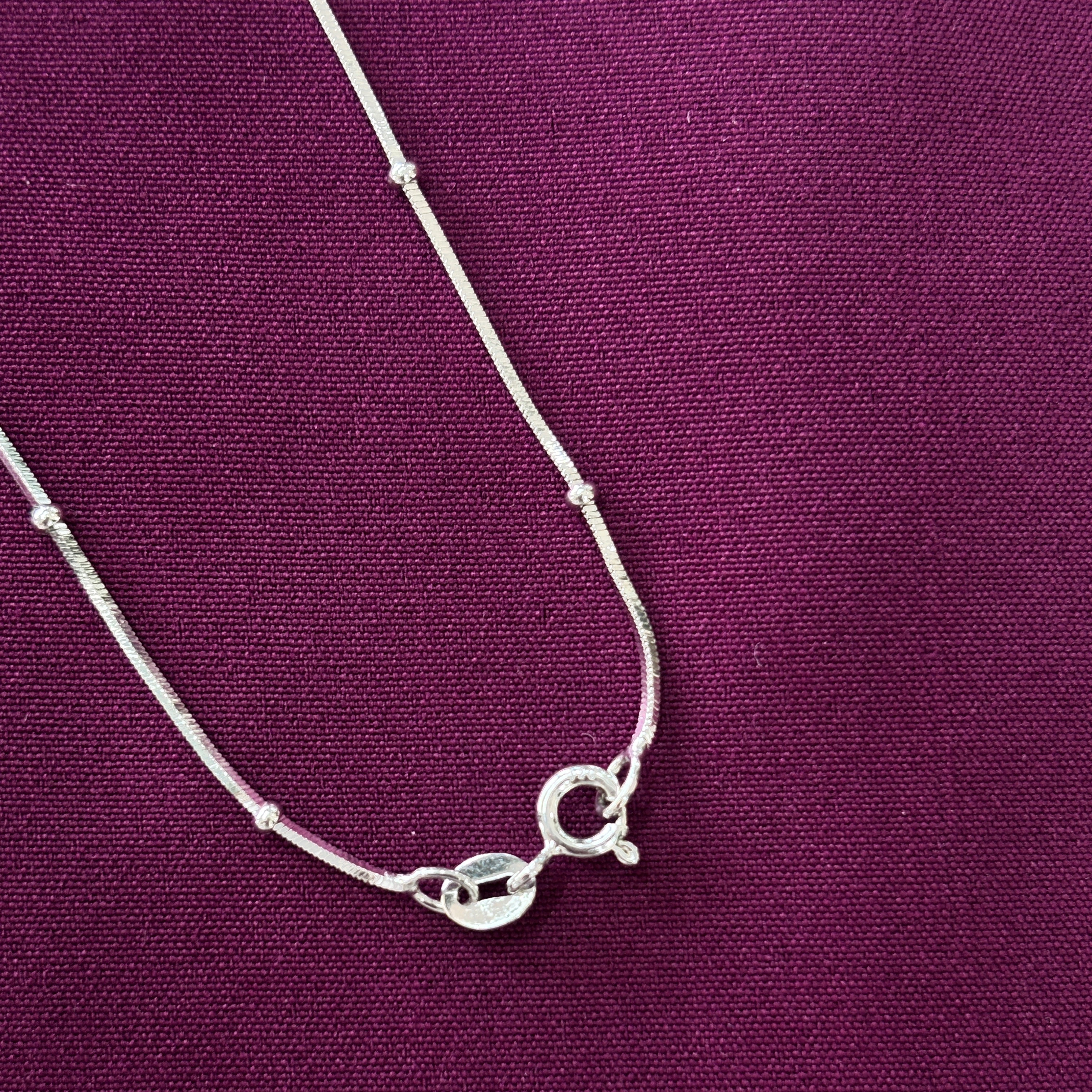 Silver chain clasp on a purple fabric background