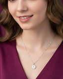 Close-up of a woman wearing a silver necklace with a round pendant.