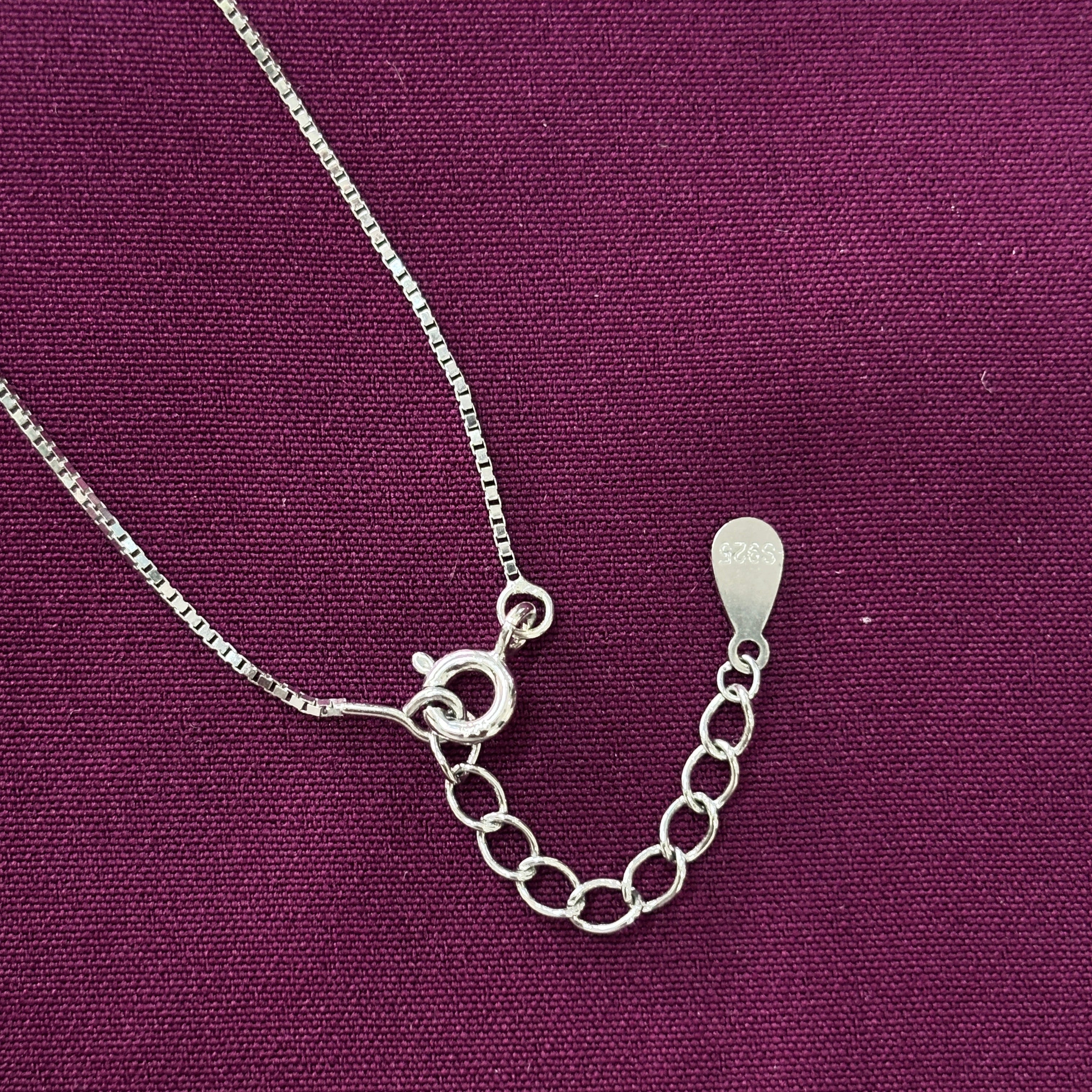 Silver chain pendent clasp on a purple fabric background