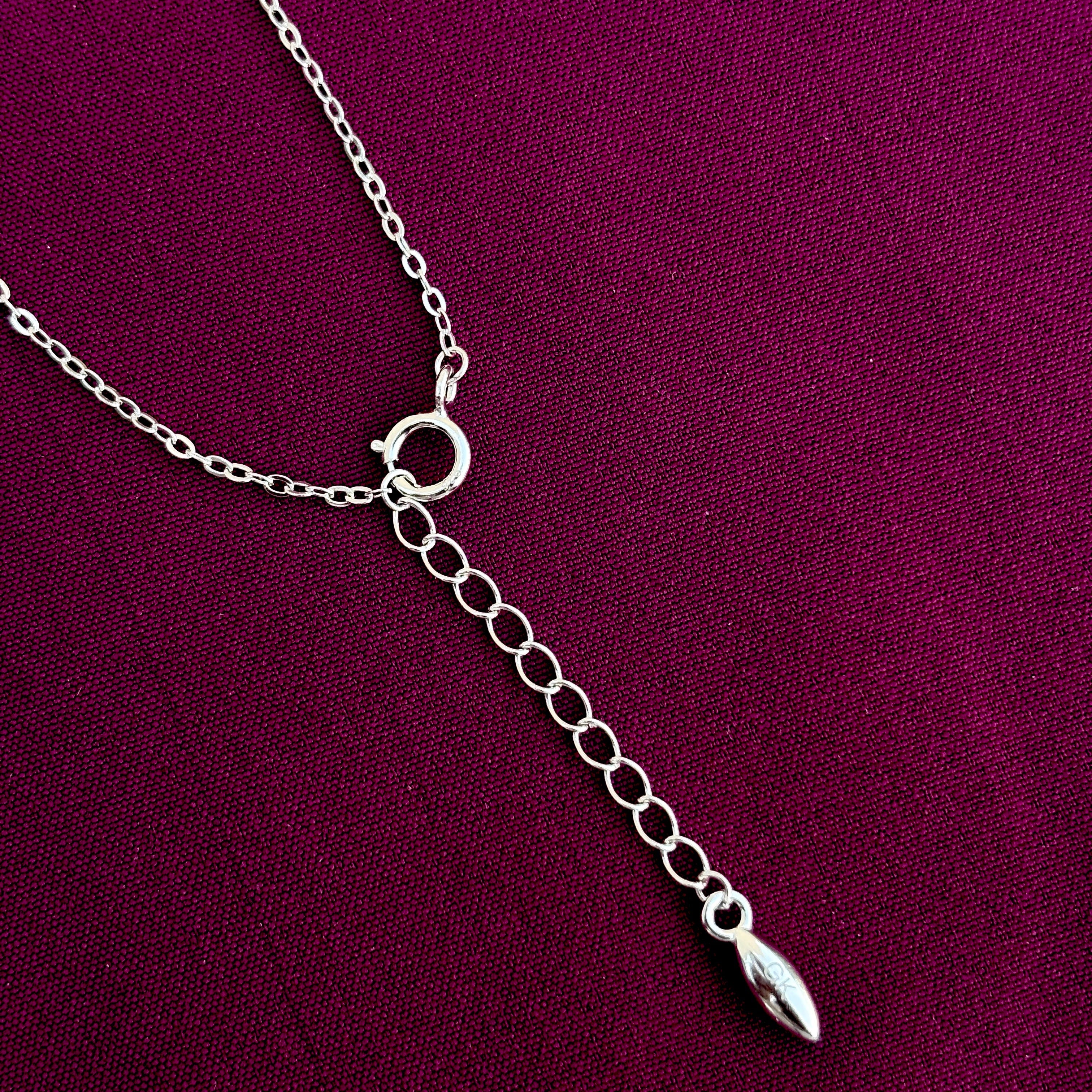 Silver necklace with a pendant on a purple fabric background