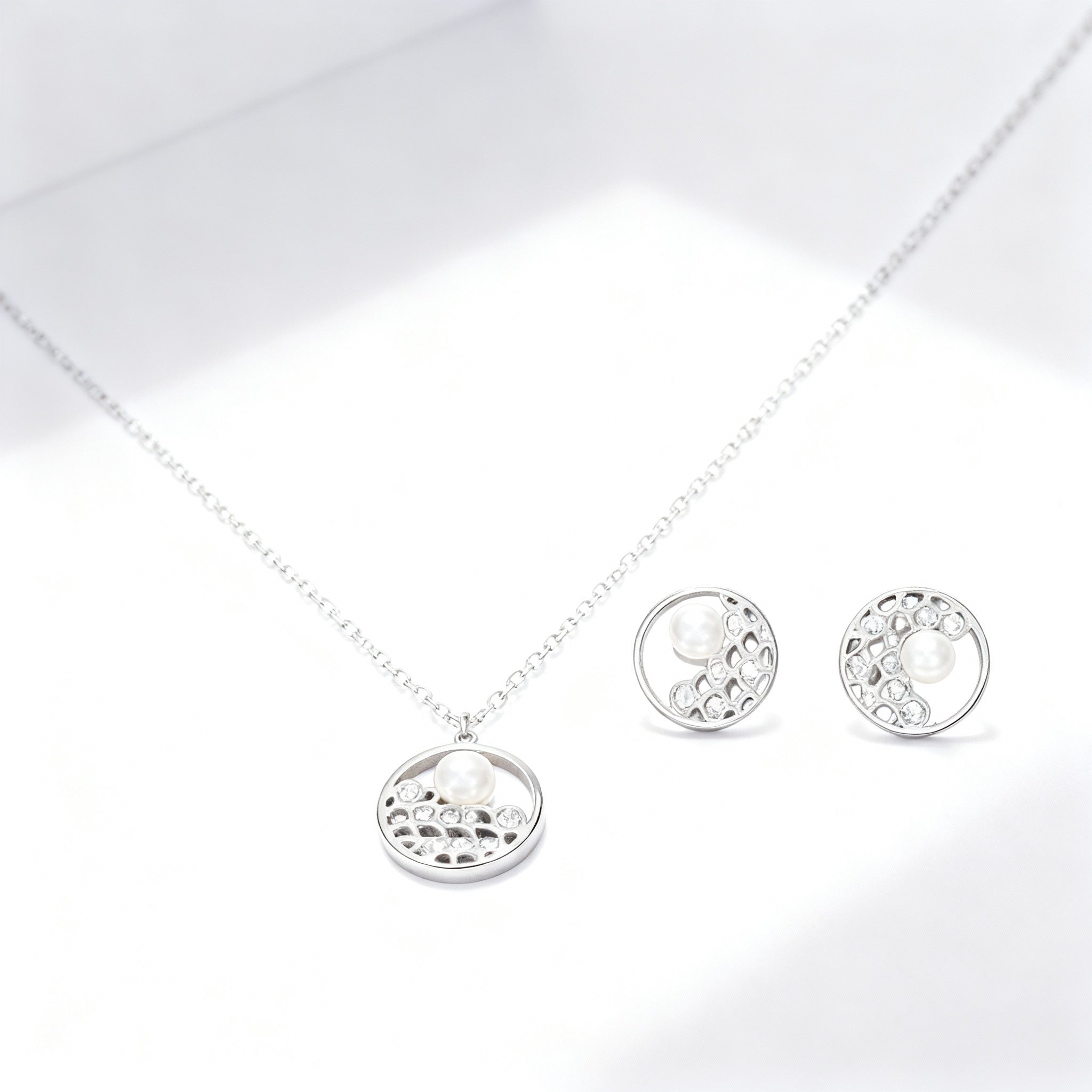 Silver necklace and earrings set on a light gray background