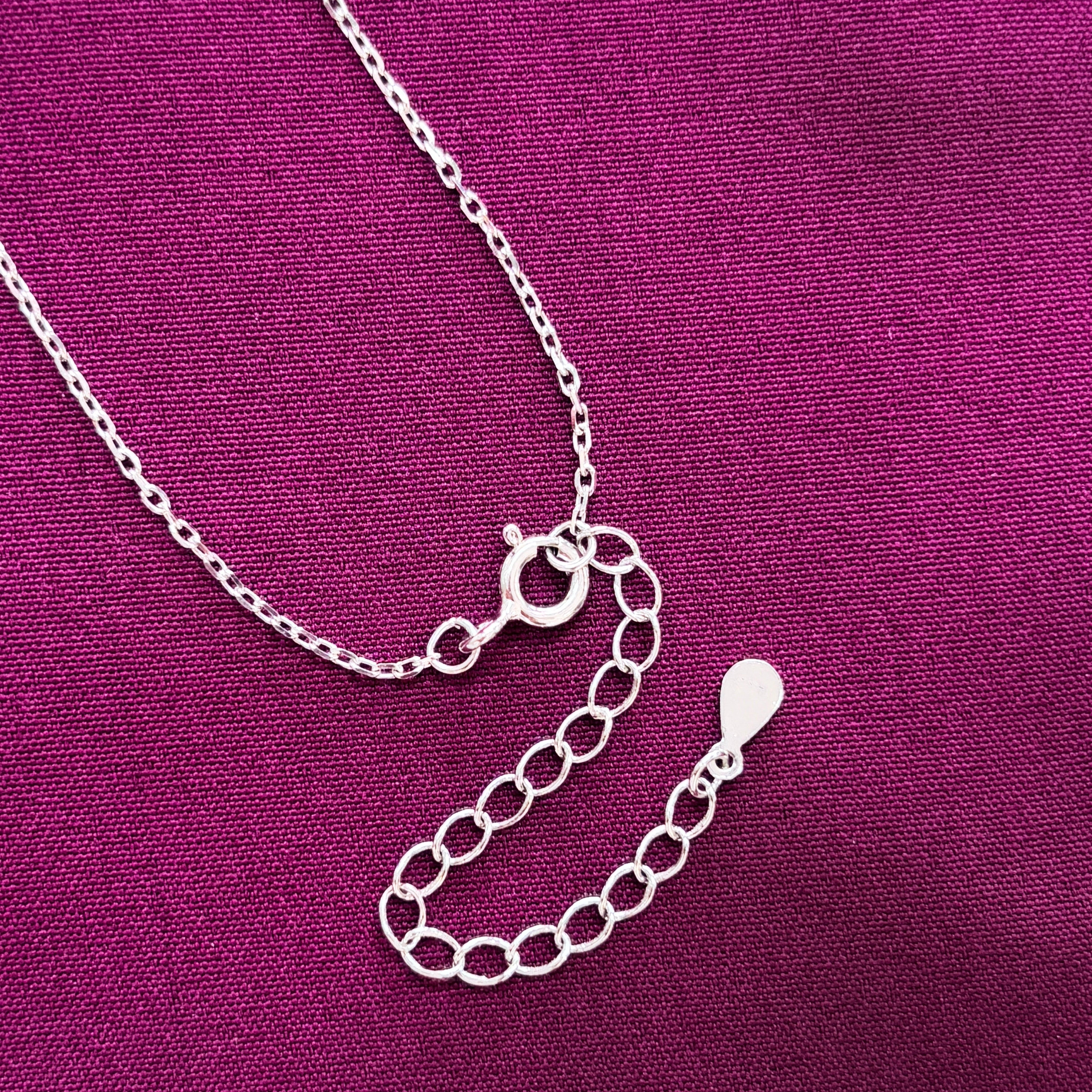 Silver necklace on a purple fabric background
