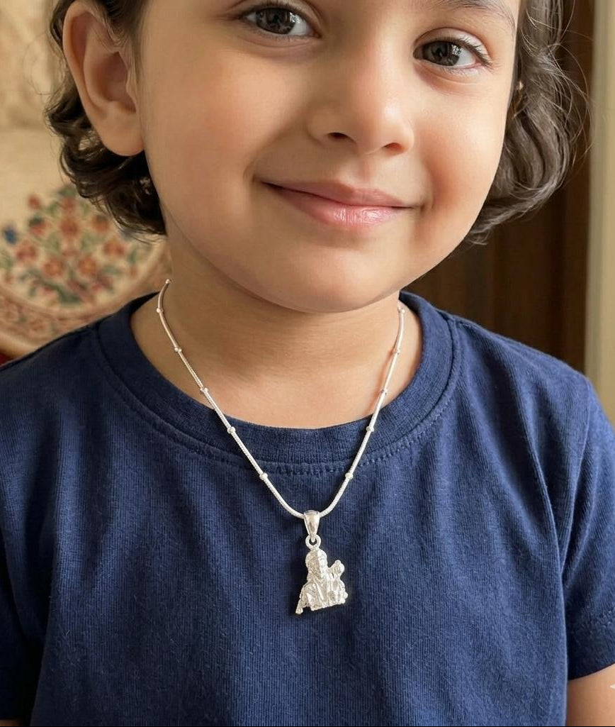 Child wearing a blue shirt with a necklace featuring a silver pendant