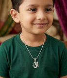 Child wearing a green shirt and silver necklace with a pendant