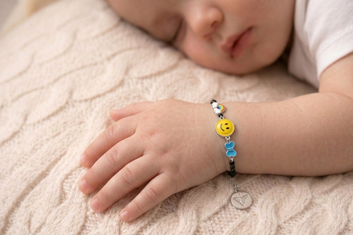 Child's hand wearing a colorful silver bracelet with smiley face charms on a soft surface