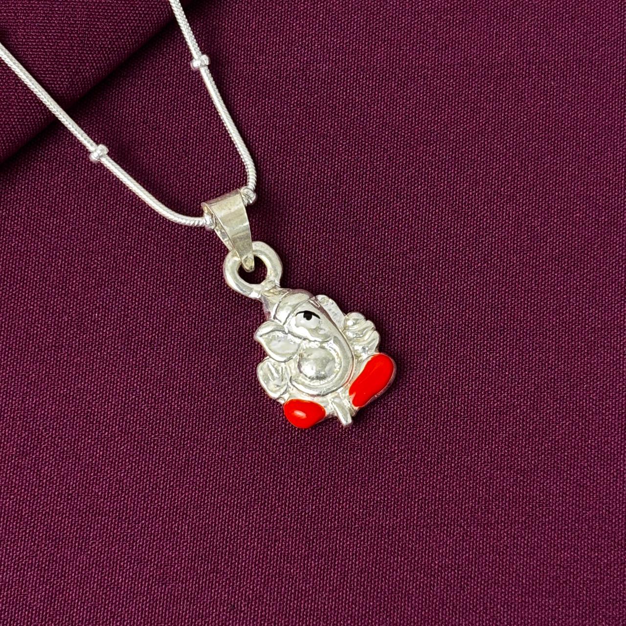 Silver pendant with red accents on a purple fabric background