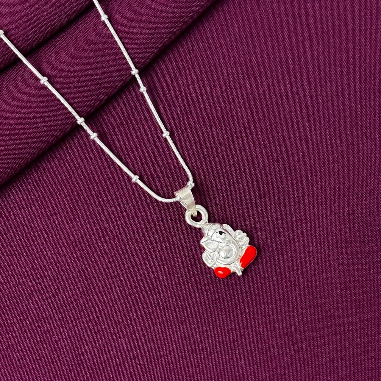 Silver necklace with a ganesha pendant on a purple fabric background