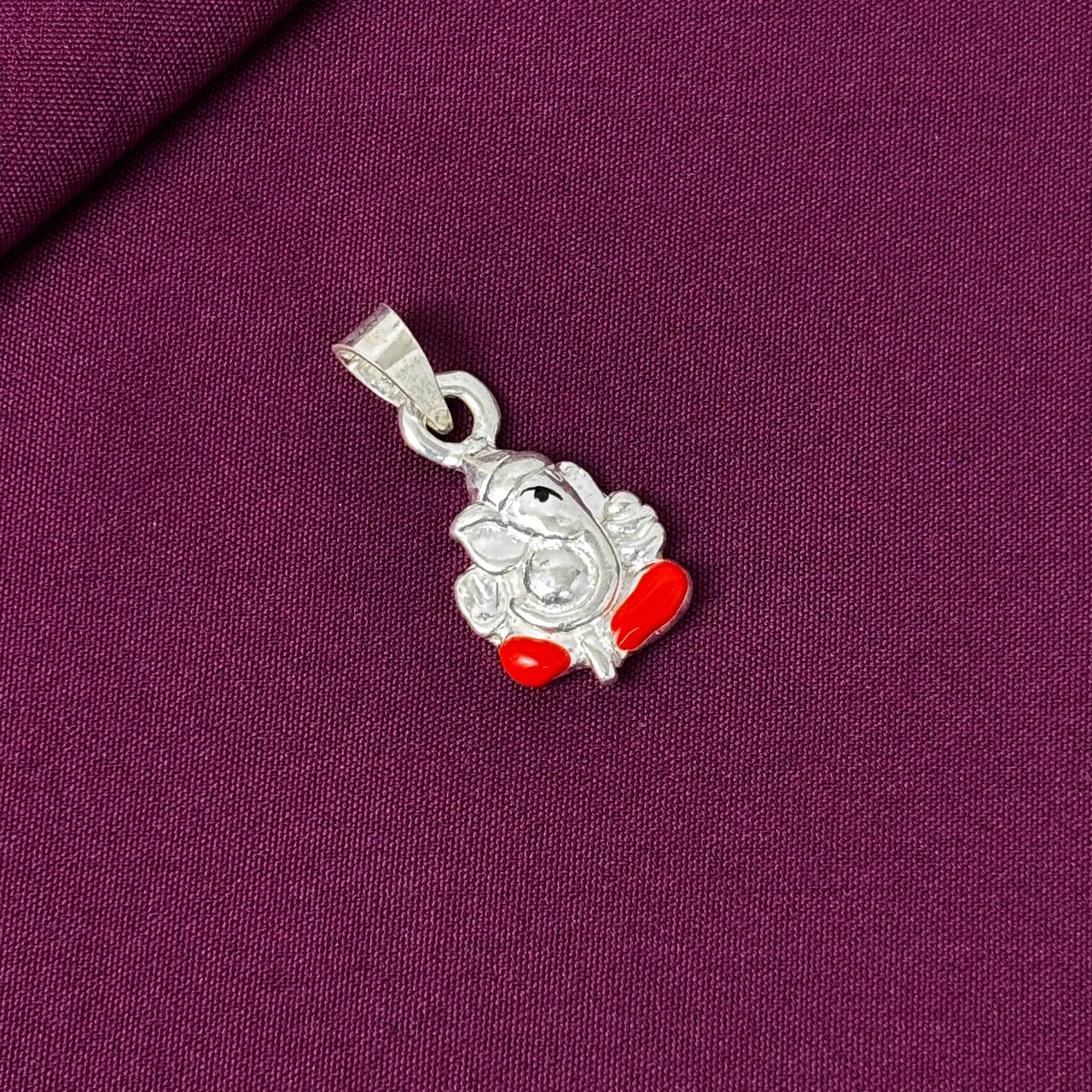 Silver pendant with red accents on a purple fabric background