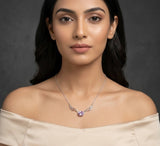 Woman wearing a necklace with a purple gemstone against a dark background