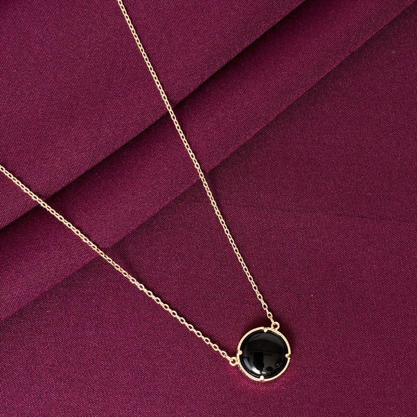 Necklace with a black pendant on a purple fabric background