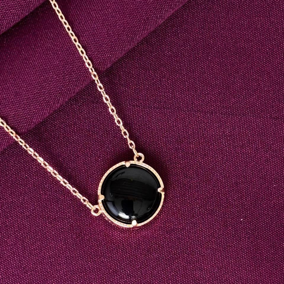 Necklace with a black pendant on a purple fabric background
