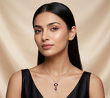 Woman wearing a black dress and a necklace with a red gemstone on a beige background