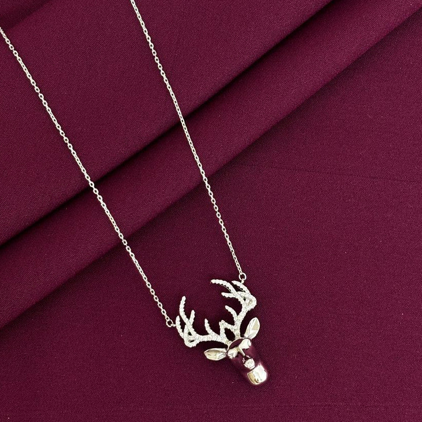 Necklace with a deer head pendant on a burgundy fabric background