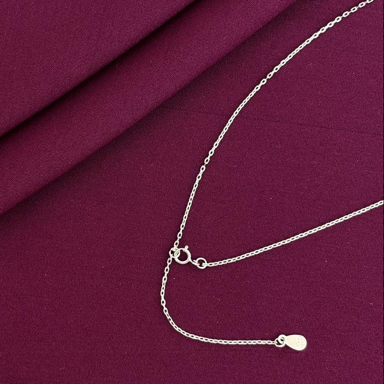Silver necklace on a burgundy fabric background