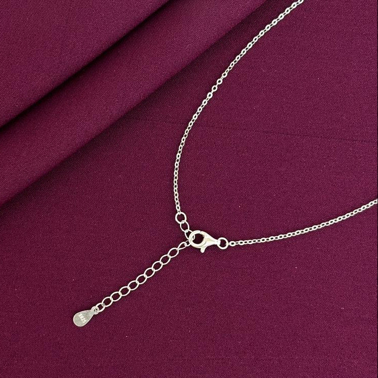 Silver necklace on a burgundy fabric background