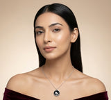 Woman wearing a necklace with a black pendant against a beige background