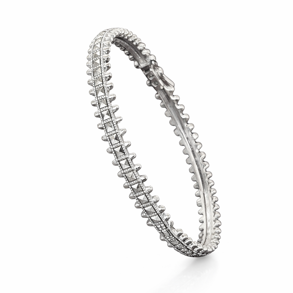 Silver kada with intricate design on a white background