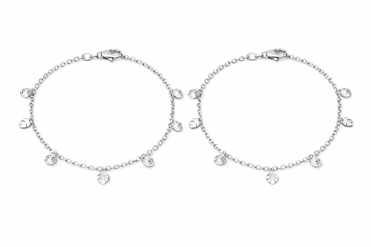 Two silver anklets with small round charms on a white background