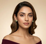 Woman wearing green earrings against a beige background