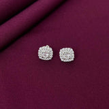 Silver earrings on a purple fabric background